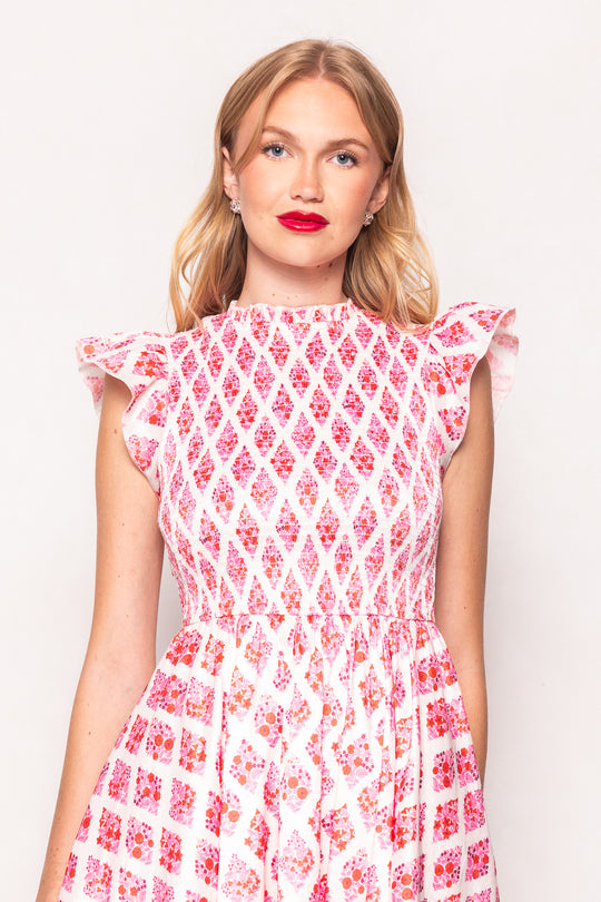 Woman wearing a red and white patterned dress against a plain background