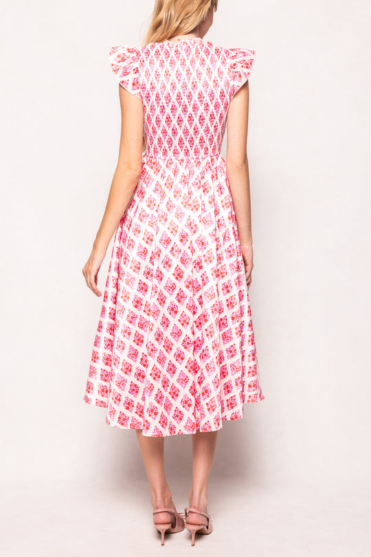 Woman wearing a pink and white patterned dress on a plain background