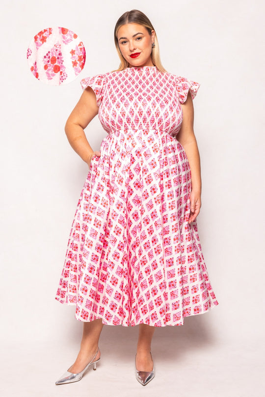 Woman wearing a red and white patterned dress on a light pink background