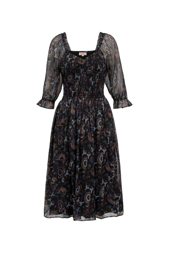The Maddison Dress in Enchanted Floral by Ivy City Co features a black midi silhouette adorned with a subtle pattern in shades of blue and brown. Designed with sheer puffed sleeves, a square neckline, and a smocked bodice, this flowy dress is both stylish and maternity friendly.