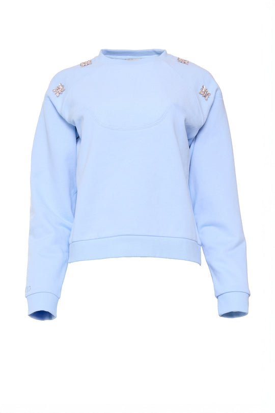 The Ivy City Co Casey Crewneck Sweatshirt in Light Blue features long sleeves and decorative crystal details on the shoulders, set against a plain white background.