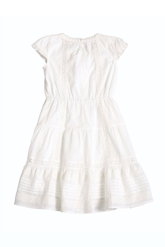 Mini Palermo Dress in White by Ivy City Co—this girls’ white short-sleeved dress features a smocked bodice, delicate lace trim, a cinched waist, and a ruffled hem, displayed flat on a white background.