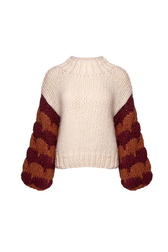 The Aimee Sweater in Orange & Cream by Ivy City Co is a chunky knit wool blend with a cream body and oversized sleeves featuring orange and brown stripes. Ribbed neckline, hem, and cuffs complete this cozy style.