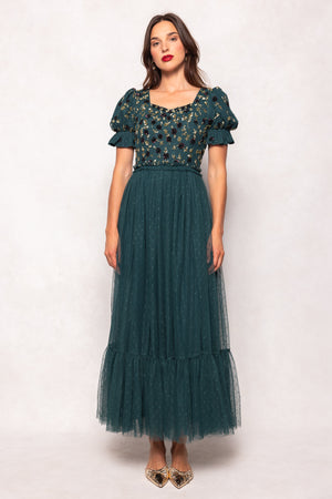 Woman wearing a green dress with floral top and tulle skirt on a white background