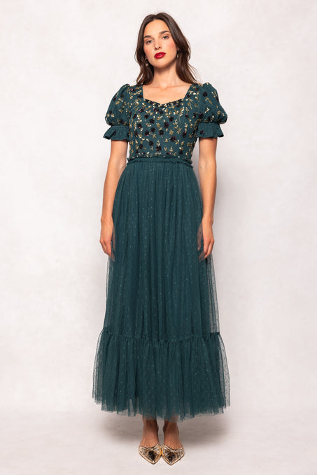 Woman wearing a green dress with floral top and tulle skirt on a white background