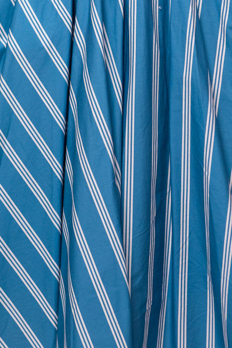 The Adelaide Dress in Blue by Ivy City Co features blue and white stripes in diagonal and vertical patterns. This cotton midi dress is stylishly gathered, adding texture and depth to its dynamic design.