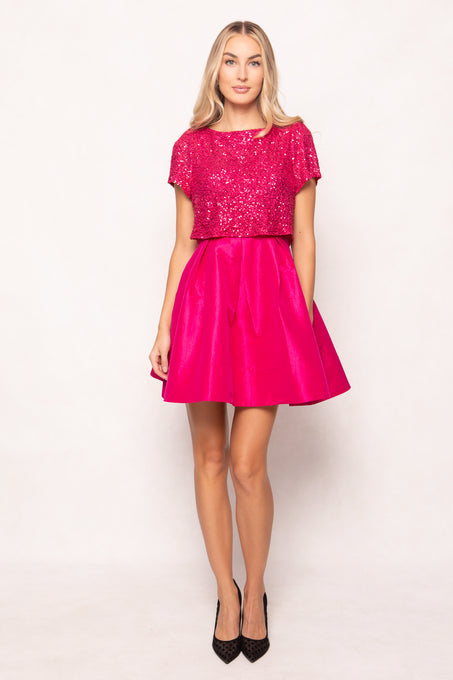 Woman wearing a pink dress with sequin top on a white background