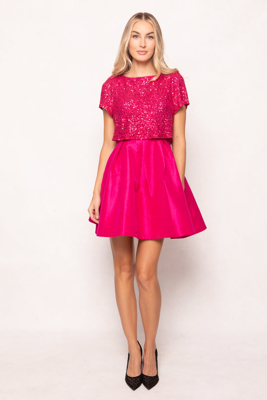 Woman wearing a pink dress with sequin top on a white background