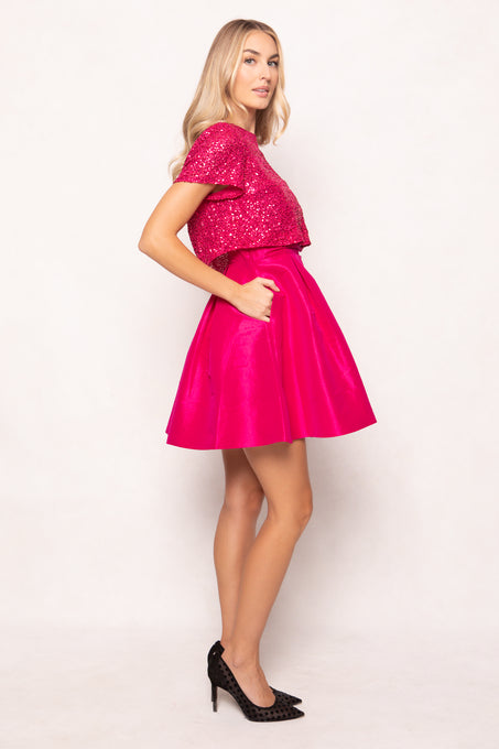 Woman wearing a pink sequin top and skirt on a white background