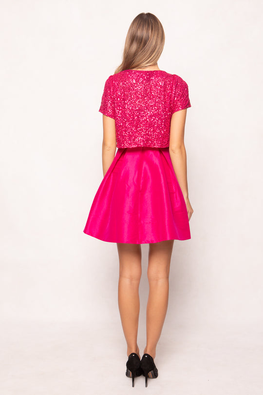 Person wearing a pink sequin top and skirt on a white background