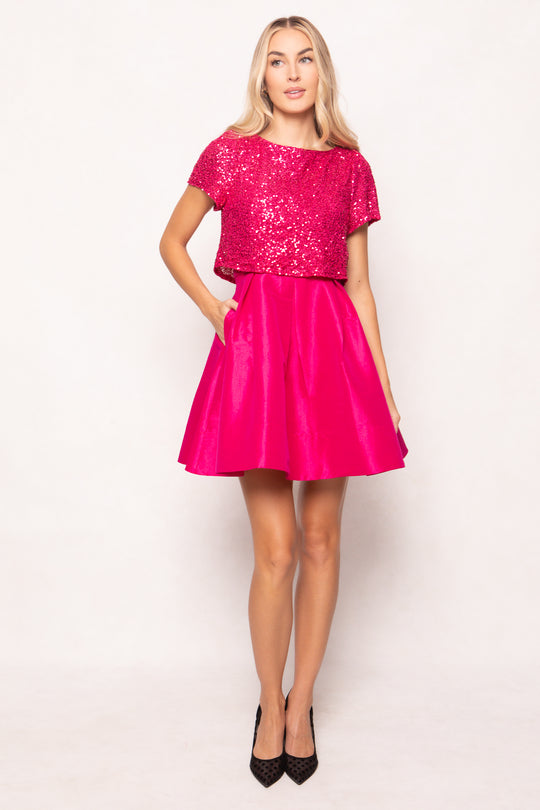 Woman wearing a bright pink sequin top and skirt on a white background