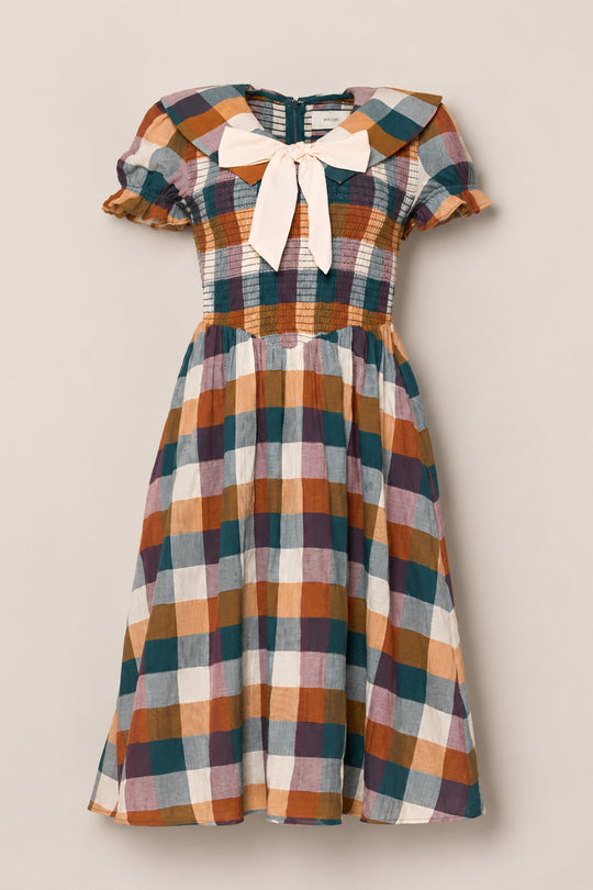 The Alice Dress in Maize Gingham by Ivy City Co showcases a short-sleeve midi silhouette with a vibrant gingham pattern, smocked bodice, and delightful puff sleeves. A cream bow adorns the neckline, while the gathered skirt drapes elegantly from the waist.