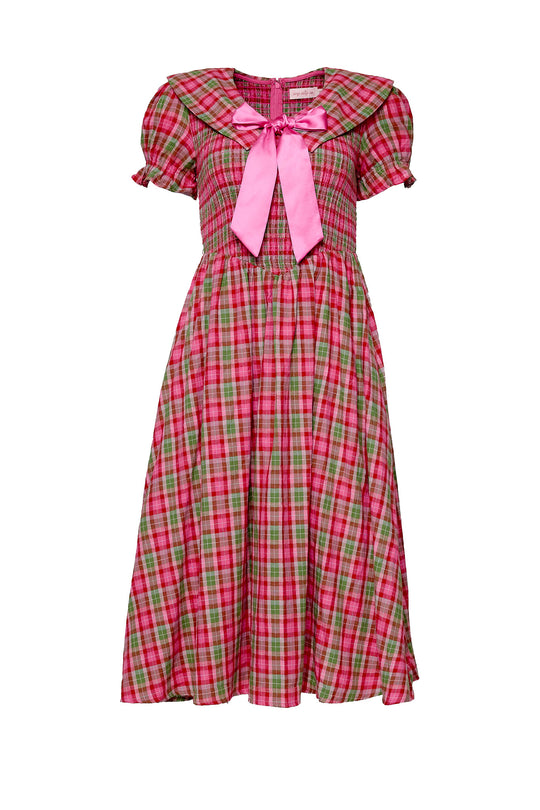 Pink and green plaid dress with a pink bow on a white background