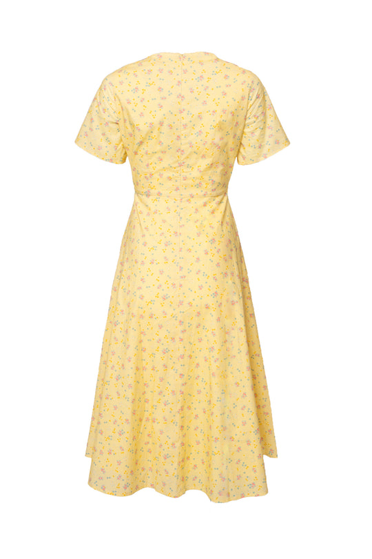 The Allie Dress in Yellow Floral by Ivy City Co is a cotton midi with an A-line cut, short sleeves, fitted waist, and flowy skirt. Shown from the back, it offers easy comfort and style in a cheerful floral print.