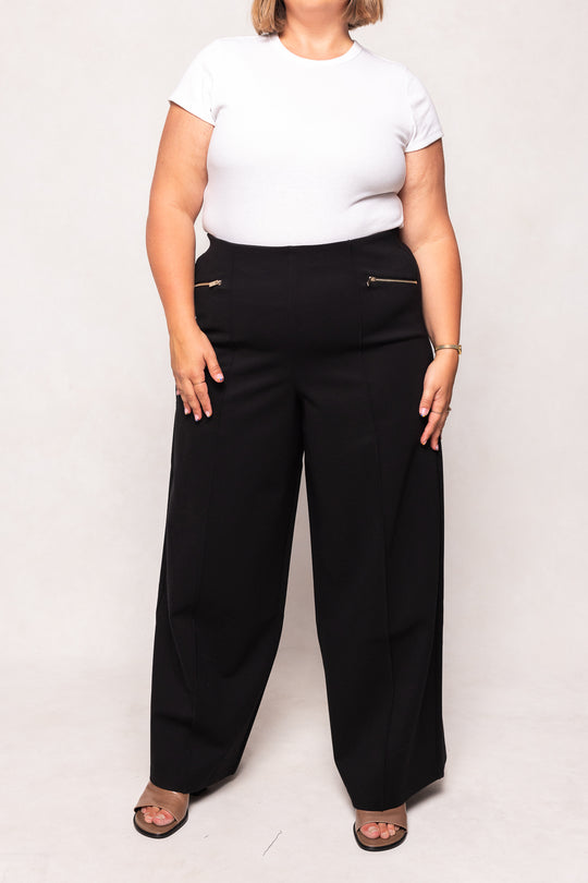 Person wearing a white t-shirt and black wide-leg pants on a plain background