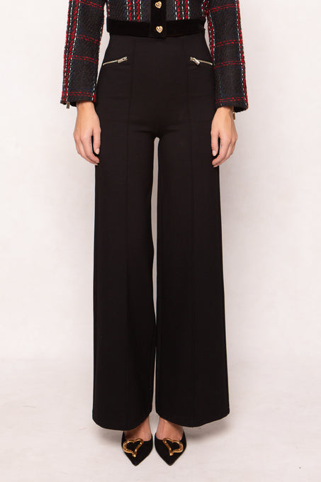 Person wearing black high-waisted pants with a plaid jacket on a white background