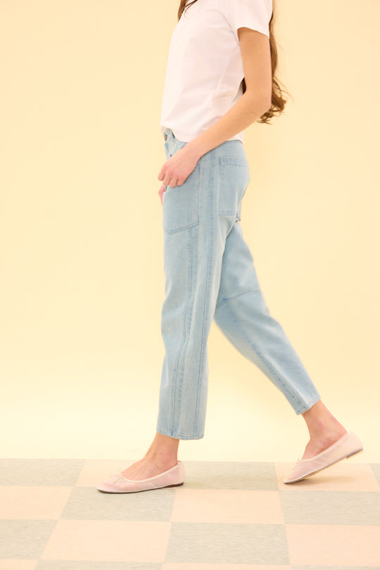 Person wearing light blue jeans and a white shirt on a checkered floor with a yellow wall background