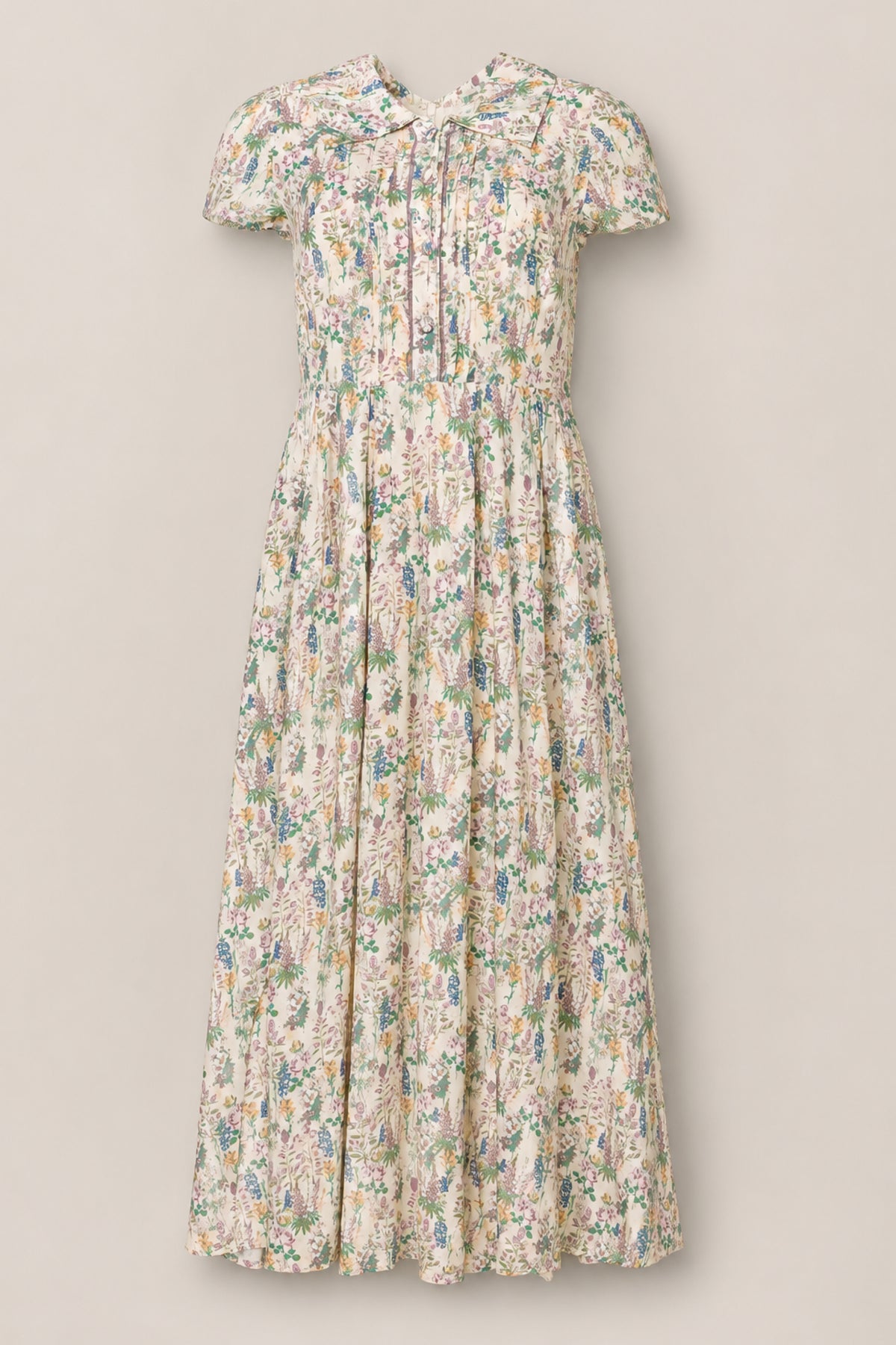 The Amber Dress in Autumn Bouquet by Ivy City Co features a vintage-inspired design with short sleeves, a tea-length silhouette, and a soft floral print. Its fitted bodice, front buttons for nursing-friendly access, and gathered skirt add timeless charm to any occasion.