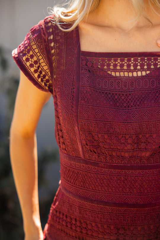 Close-up of a person wearing a red lace dress with a blurred background