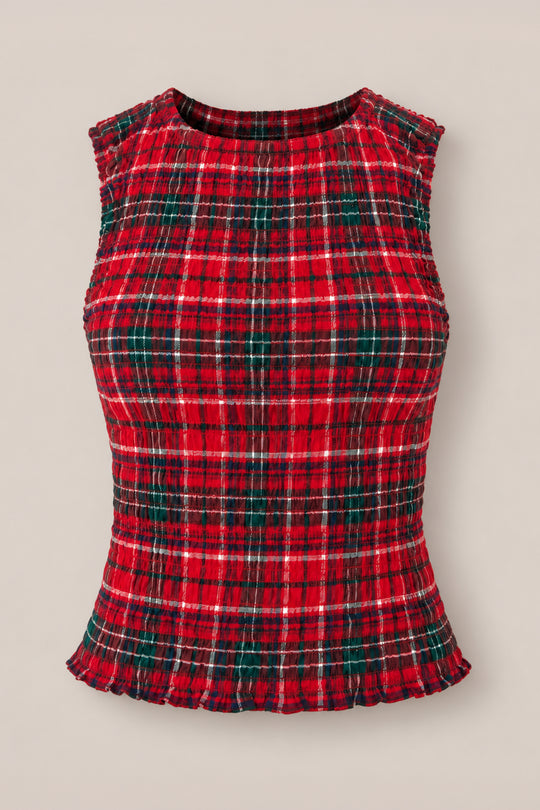 The Ana Top in Christmas Cheer Plaid by Ivy City Co is a sleeveless, fitted girls holiday tank featuring green and white stripes on red plaid, a ribbed texture, and ruffled edges at the hem and armholes—shown here against a plain beige background.