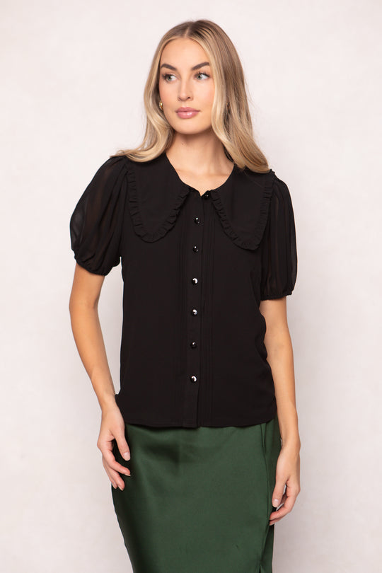 Woman wearing a black blouse with a large collar against a white background