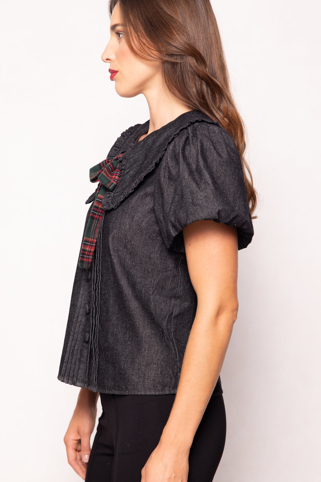 Woman wearing a dark gray top with plaid accents on a white background