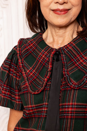 Person wearing a green and red plaid jacket with a white background