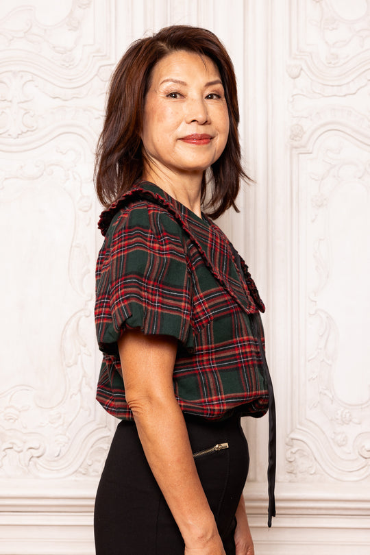 Woman wearing a plaid jacket against a white wall