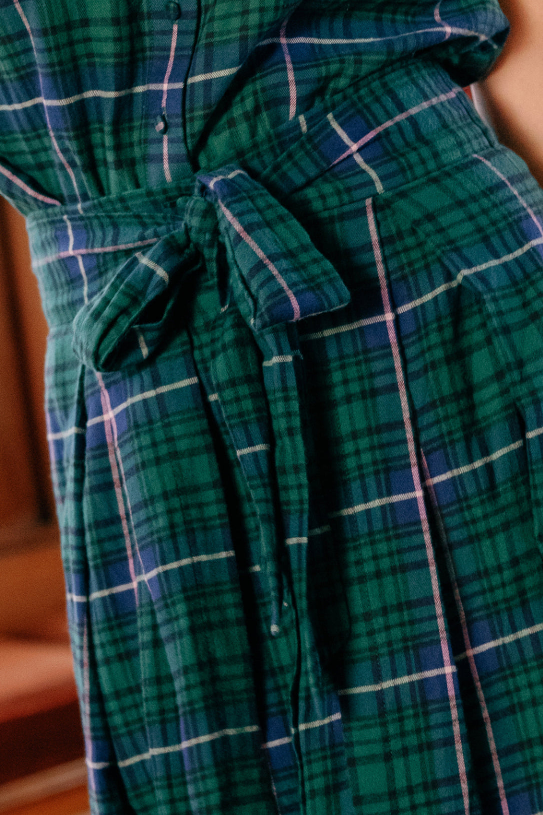 Close-up of the Angela Skirt in Emerald Plaid by Ivy City Co, featuring a green and blue plaid pattern accented with thin white and pink lines. The skirt is styled with a tied belt around the waist, making it perfect for holiday portraits.