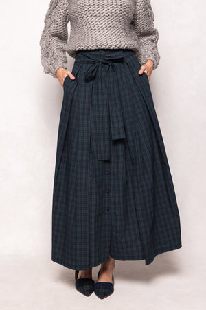Person wearing a long dark plaid skirt and light gray sweater on a white background