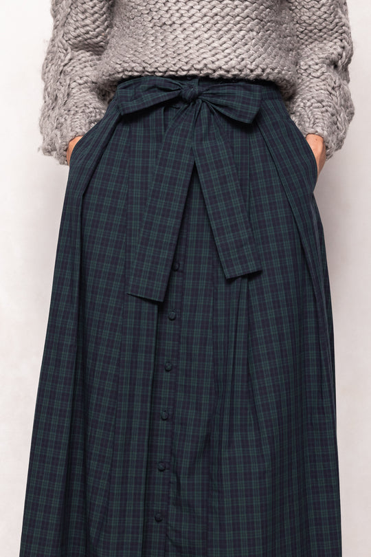 Navy plaid skirt with a bow tie waist worn by a person on a white background
