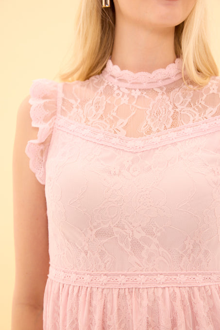 Close-up of a pink lace dress on a person with a yellow background