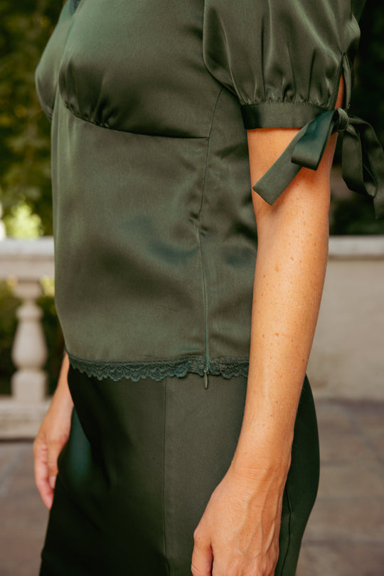 Green outfit with a bow detail on a blurred outdoor background