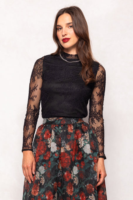 Woman wearing a black lace top and floral skirt on a white background
