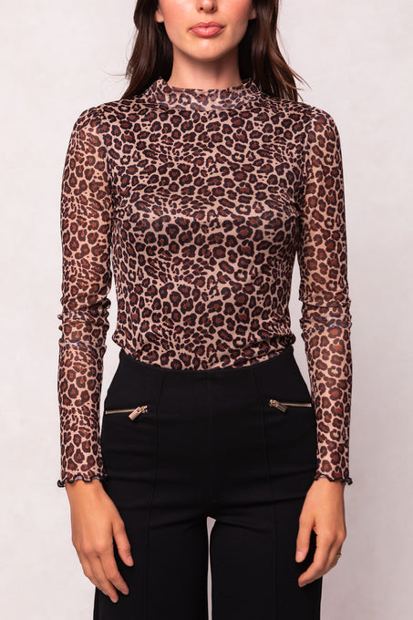 A woman models the Ivy City Co Ava Long Sleeve Top in Leopard— a fitted, sheer mesh piece—paired with high-waisted black pants with gold zippers. She is shown from shoulders to hips against a plain background.