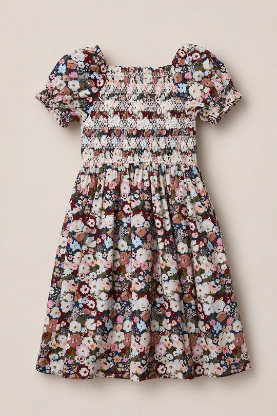 Introducing the Mini Sunday Best Dress in Midnight Garden by Ivy City Co—a delightful girls’ short-sleeve dress with a smocked bodice and adorable puff sleeves. Its colorful floral pattern on a midnight background brings playful elegance, while the gently gathered skirt ensures a beautifully flowing silhouette.