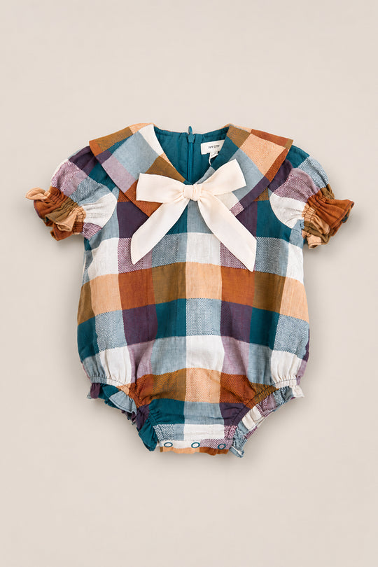 The Baby Alice Romper in Maize Gingham by Ivy City Co is a charming plaid cotton-blend romper featuring puff sleeves, a large sailor-style collar, a cream bow at the neckline, and gathered leg openings. The fabric showcases teal, brown, purple, and white checks for a classic touch.