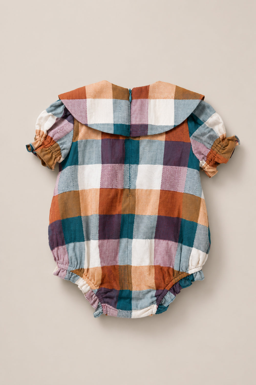 The Ivy City Co Baby Alice Romper in Maize Gingham is a charming cotton-blend romper with a large plaid pattern in blue, orange, brown, and white. It features short puff sleeves, a Peter Pan collar, and elastic leg openings. The garment is displayed flat on a neutral background.