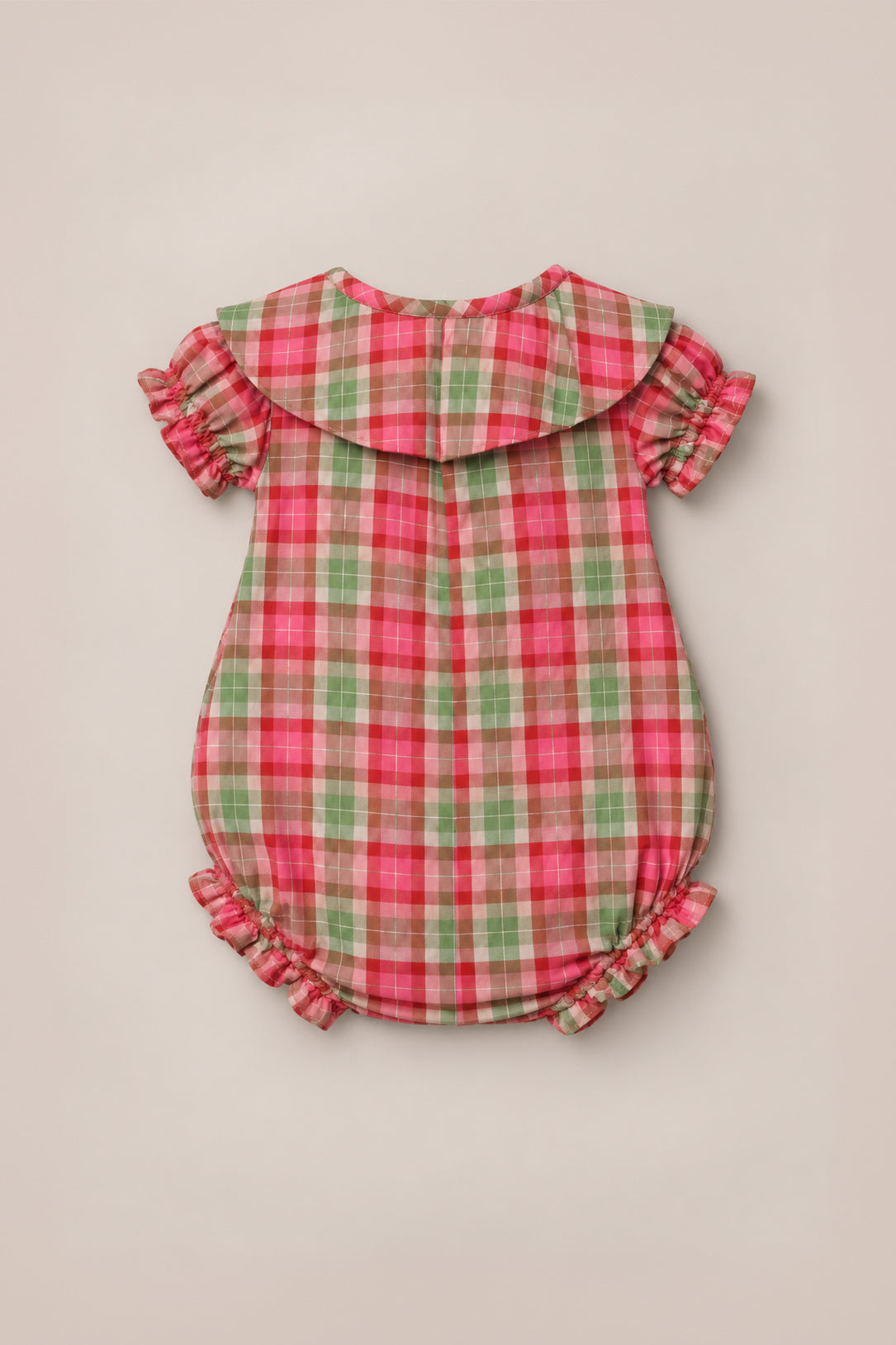 The Ivy City Co Baby Alice Romper in Rosewood Tartan, crafted from cotton plaid fabric in red, green, and pink tartan, features puffed short sleeves, ruffled trim at the sleeves and legs, and a wide Peter Pan collar. The romper is displayed flat on a neutral background.