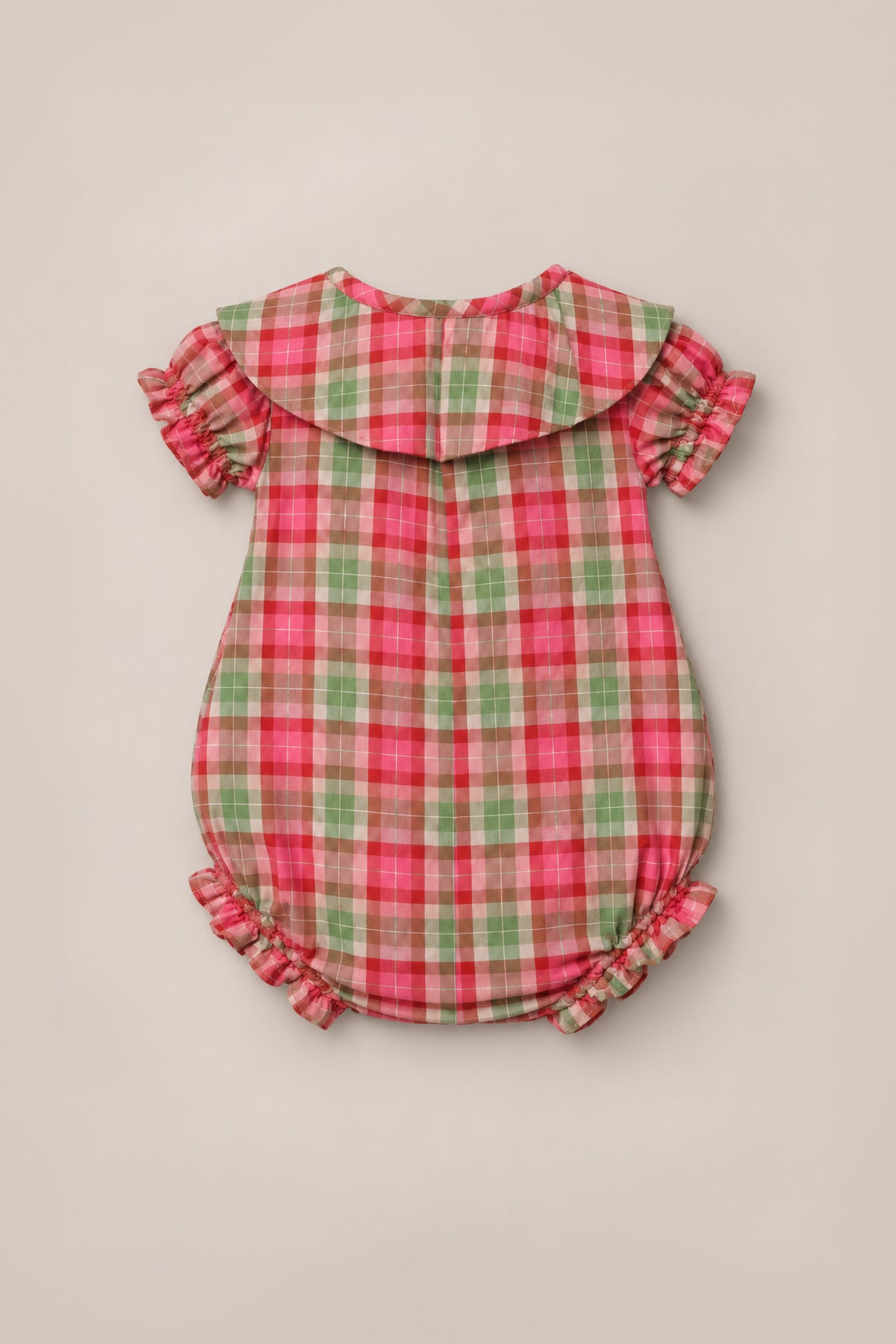 The Ivy City Co Baby Alice Romper in Rosewood Tartan, crafted from cotton plaid fabric in red, green, and pink tartan, features puffed short sleeves, ruffled trim at the sleeves and legs, and a wide Peter Pan collar. The romper is displayed flat on a neutral background.