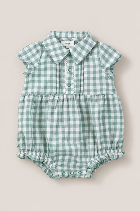 The Ivy City Co Baby Amber Romper in Sage Gingham features green and white cotton, short sleeves, a collar, button placket, and gathered leg openings. The vintage-inspired romper is shown laid flat on a neutral background.