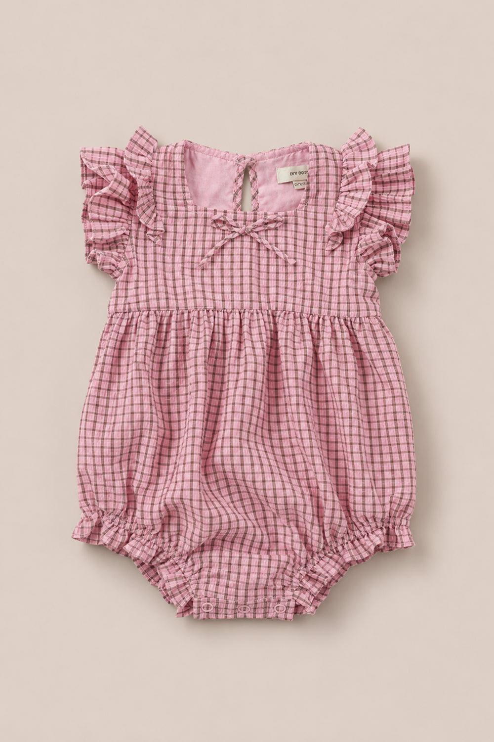 Ivy City Co’s Baby Ana Romper in Pink & Brown Gingham features flutter sleeves, a gathered waist, elastic leg openings, and a small neckline bow, shown on a neutral background.