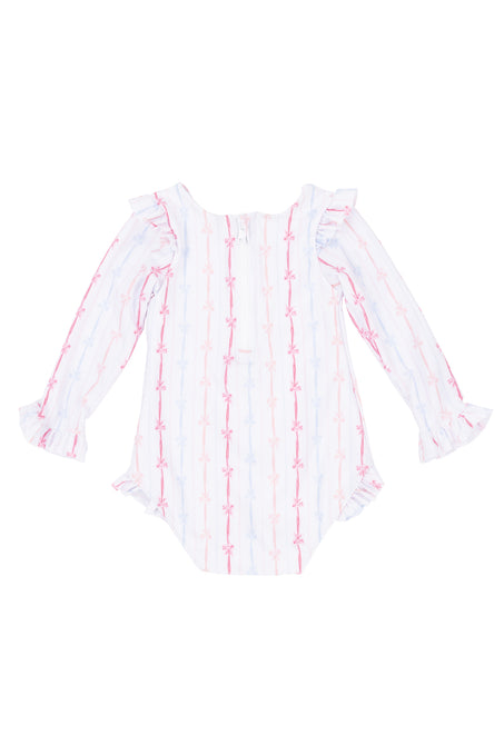 The Ivy City Co Baby Bella Rash Guard in Breea Bow features long sleeves, ruffled cuffs, and a pastel pink and blue bow swimsuit print on white, displayed flat against a white surface.