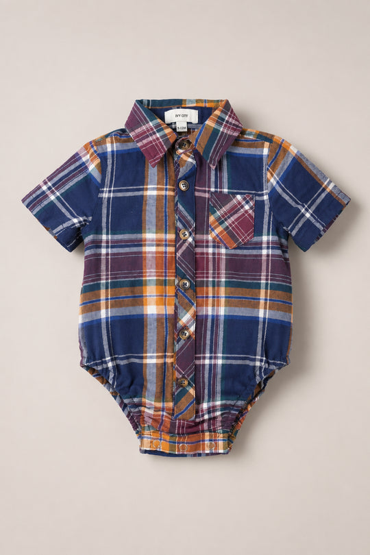 The Ivy City Co Baby Boy James Romper in Midnight Plaid features short sleeves, a multicolored plaid button-down design with front buttons, a collar, and a small chest pocket, displayed laid flat on a neutral background.