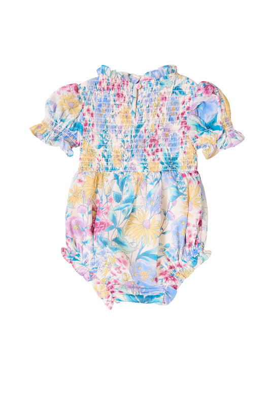 The Ivy City Co Baby Cordelia Romper in Pretty Plumeria has pastel hues, short puffed sleeves, a ruffled collar, and smocked details—a sweet spring romper for your little one.