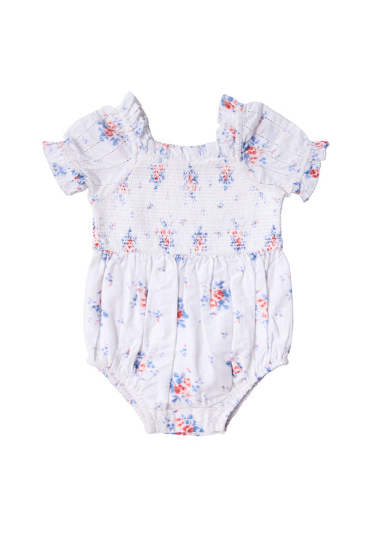The Baby Emily Romper in Heritage Soft Ditsy Floral by Ivy City Co features a white ditsy print, short ruffled sleeves, smocked bodice, blue and pink florals, and gathered legs—ideal for a sweet mom and me matching look.