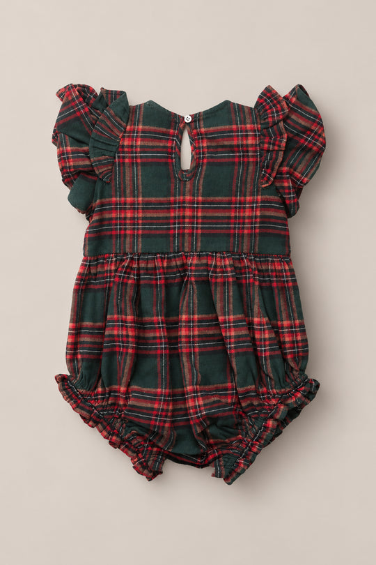 The Baby Hattie Romper in Evergreen Plaid by Ivy City Co is a charming holiday romper featuring a festive red and green plaid print. It has short ruffle sleeves, a gathered waist, and elastic leg openings for added comfort. The back is finished with a small button closure at the neck.