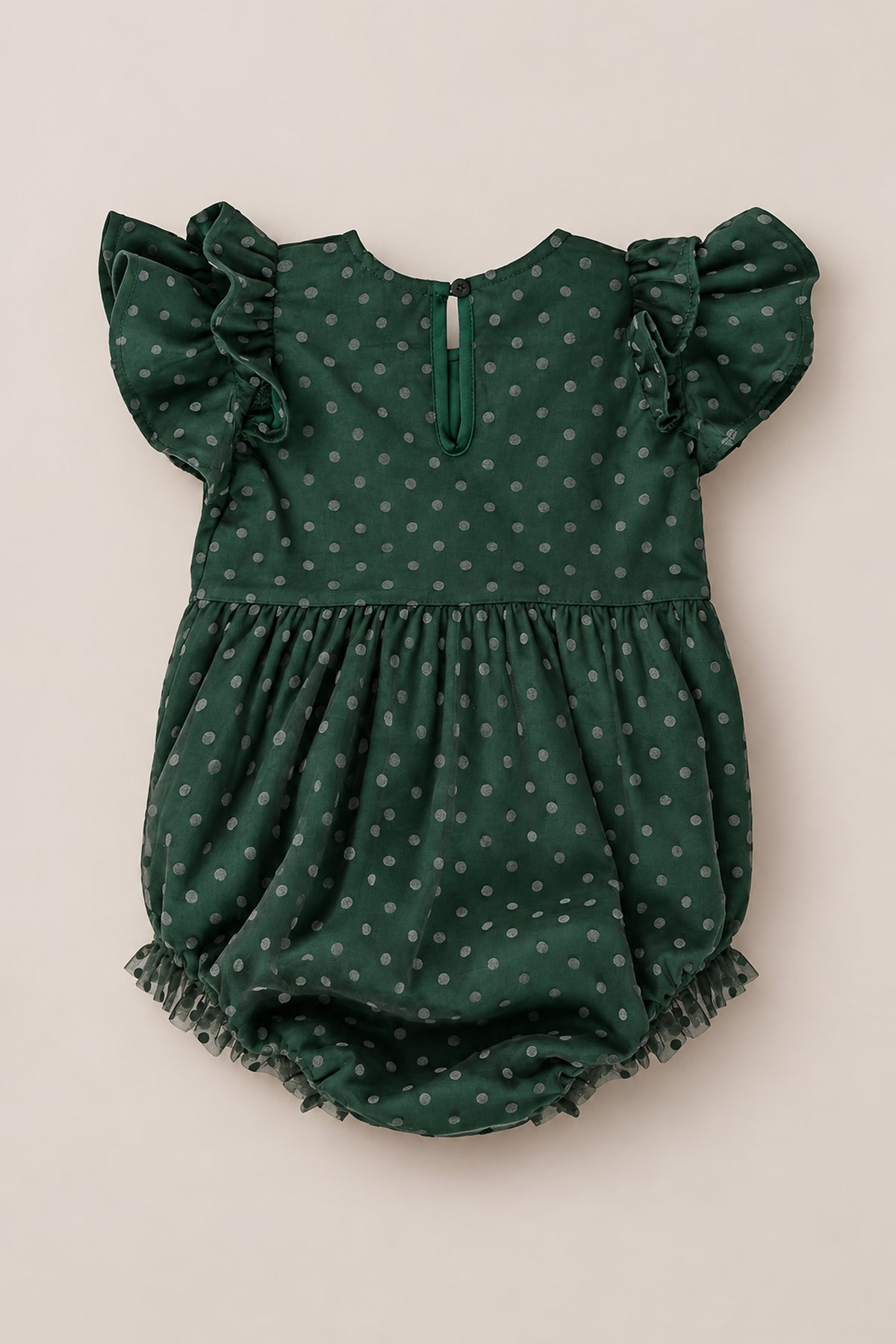 The Ivy City Co Baby Hattie Romper in Green Flocked Dot Tulle showcases a rich green color adorned with delicate flocked dots. Designed with charming ruffled short sleeves, a gathered waist, and playful ruffled leg openings, this romper is crafted from soft tulle for ultimate comfort. Finished with a subtle button closure at the back of the neck, it’s beautifully displayed against a neutral backdrop—making it an ideal choice for family photos or special occasions.