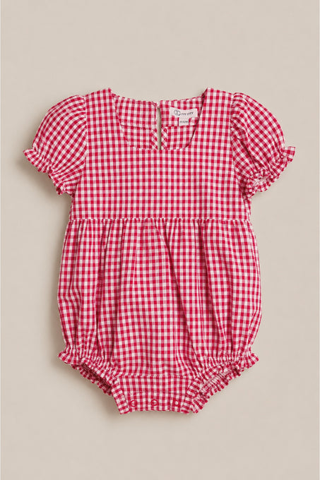 The Baby Jessie Romper in Red Gingham by Ivy City Co features short puff sleeves, ruffled edges, a gathered waist, back buttons, and elastic leg openings—ideal for the Fourth of July. Shown laid flat on a neutral background.