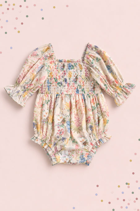 The Ivy City Co Baby Madeline Romper in Cordelia Floral features long puffed sleeves, ruffled cuffs, and a smocked bodice on pale pink with pastel confetti dots—perfect for adorable mommy-and-me moments.